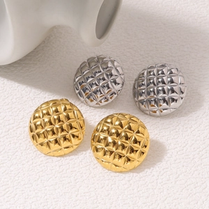 Close-up of gold and silver round stud earrings featuring classic quilted pattern texture