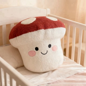 Cute red mushroom plush pillow with a smiling face on a white wooden crib