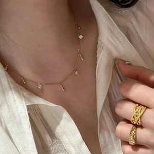 Two-tone gold cross pendant necklace and textured rings with teardrop charms on model