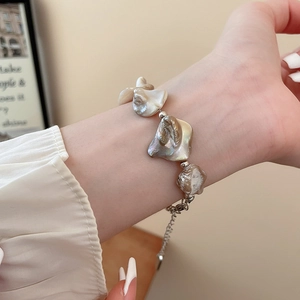 Vista dettagliata di un bracciale con perle barocche e conchiglie con catena d'argento al polso