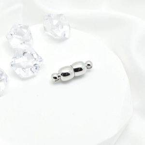 Polished silver magnetic clasp for jewelry making on white silk with clear acrylic ice