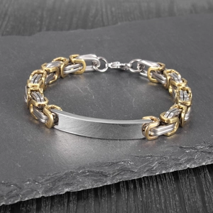 Detailed close-up of a two-tone Byzantine chain bracelet with a smooth metal ID tag
