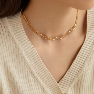 Chic 18K gold plated triple layered chain necklace worn over a beige V-neck sweater