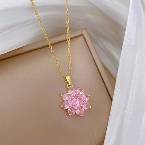 Detailed macro view of a gold flower necklace featuring pink sparkling cubic zirconia stones