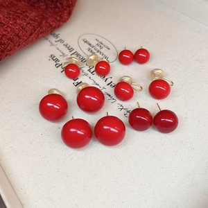 Set of six red spherical pearl earrings in various sizes on vintage fabric background