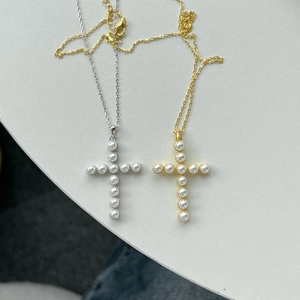 Detail of silver and gold cross necklaces featuring small white round pearls on O-chains