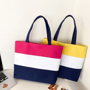 Detailed shot of pink and yellow tricolor canvas tote bags on a desk with a laptop