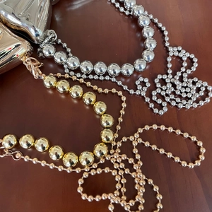 Dettaglio di catene a sfere metalliche in oro e argento con chiusura a moschettone