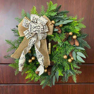 Christmas wreath with pine cones and golden bells on a rustic wooden door background