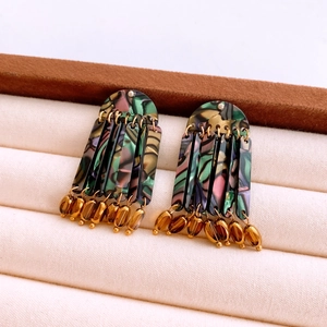 Macro view of vintage tassel earrings with green acrylic marble texture and amber beads