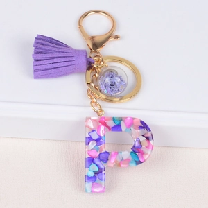 Detail of resin letter P keychain with purple tassel and dried flower glass ball