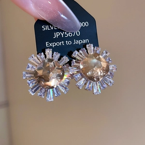 Macro shot of sparkling zircon sunflower earrings with silver needles and crystal petals