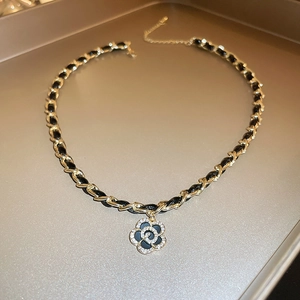 Detail of camellia flower pendant with cubic zirconia and woven leather chain