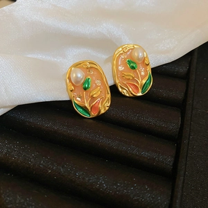 Detail of vintage French tulip pearl earrings on black velvet with white silk texture