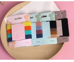 Macro detail of 16 multicolor elastic hair ties arranged neatly on a card in a tray