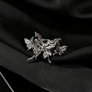 Detailed close-up of a silver butterfly ring with cut-out design on black silk fabric