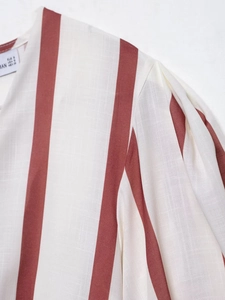 Detail of red striped dress collar with EUR S size label and cotton linen texture