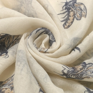 Macro detail of breathable cream fabric with golden glitter bee prints and texture