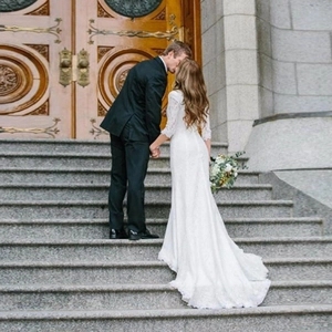 Elegant white long-sleeved lace wedding dress with V-neck and slim fit in outdoor setting