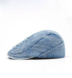 Side view of washed light blue denim flat cap with vintage embroidery and distressed detail