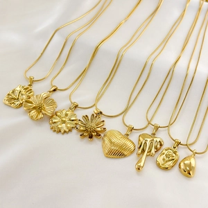 Multiple 18K gold plated titanium steel necklaces with various pendants on white silk