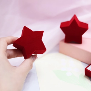 Close-up of a red star-shaped velvet jewelry box for rings and earrings in a romantic setting