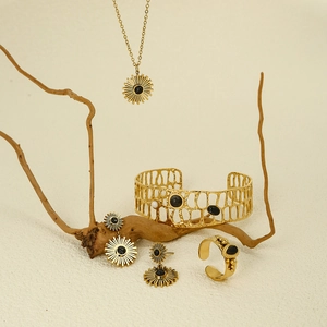 Detailed set of gold sunflower jewelry with black natural stones on rustic branch