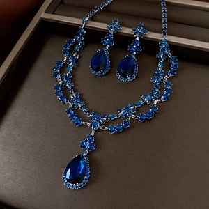 Détail macro du collier et des boucles d'oreilles en zircon bleu dans un coffret de luxe