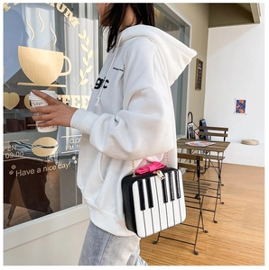 Close-up of a piano key crossbody bag with a pink bow and gold chain strap