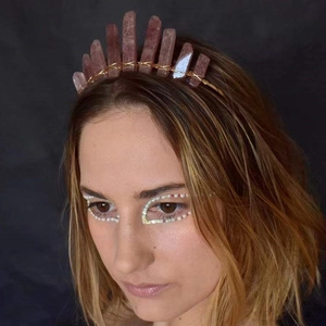 Handmade crown headband featuring raw pink crystals and golden wire wrap on female model