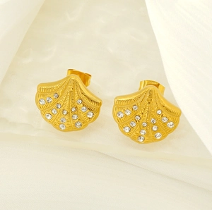 Macro shot of gold shell earrings with inlaid rhinestones on a silk background