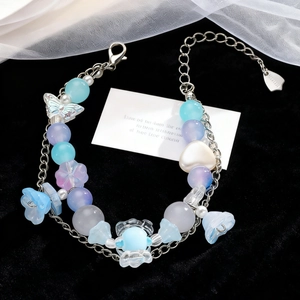 Detalle de pulsera de cuentas con flores azules y dijes de corazón en terciopelo negro