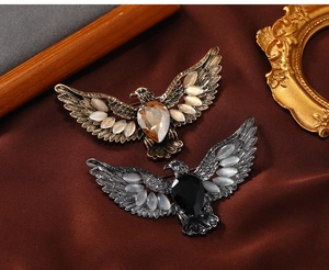 Detail of vintage eagle brooches featuring amber and black stones on silk background