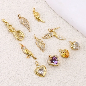 Gold plated mermaid and heart pendants with colorful zircon on beige fabric background