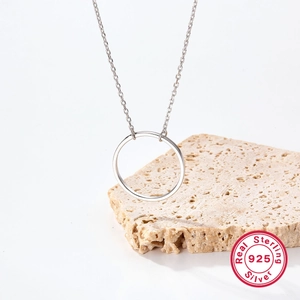 Vue macro d'un collier pendentif circulaire en argent sterling 925 sur pierre beige