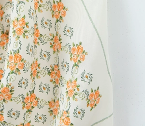 Detailed macro view of orange floral rose print on premium satin texture fabric