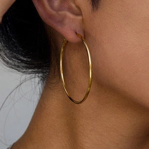 Close-up of model wearing classic 18K gold-plated stainless steel hoop earrings
