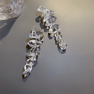 Macro shot of irregular clear acrylic ice block earrings with silver pins and reflective facets