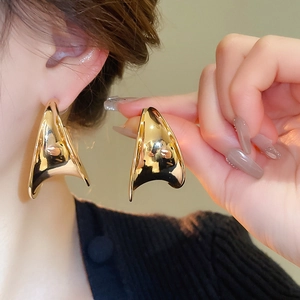 Close-up of chunky gold geometric C-shaped hoop earring on model with metallic finish