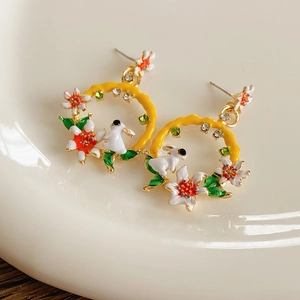 Détail de boucles d'oreilles vintage avec lapin blanc et fleurs en émail coloré