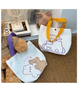Detail of cute cartoon canvas tote bags with bear prints and colorful handles in a cozy setting
