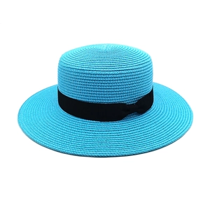 Detail of bright blue boater hat featuring fine straw texture and black ribbon bow