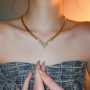 Close-up of gold-plated V-shaped necklace with shimmering diamonds on a model neck