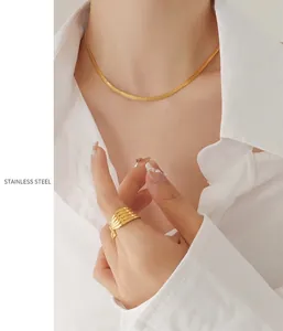 Close-up of golden stainless steel flat snake chain necklace and ribbed textured ring
