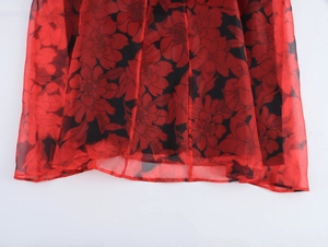 Détail du tissu en organza imprimé floral rouge et noir avec texture légère et transparente