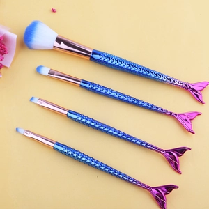 Set of four gradient mermaid tail makeup brushes with blue-white bristles on yellow background