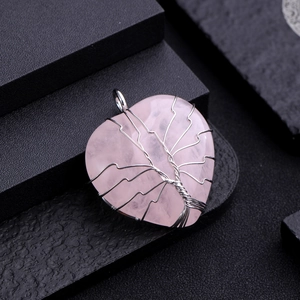 Macro detail of silver wire-wrapped rose quartz heart pendant with tree of life design