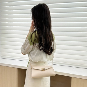 Elegant beige PU leather lady bag with gold chain strap shown on model against blinds