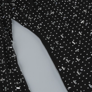 Close-up of black mesh fabric with sparkling silver rhinestones on a slim-fit dress