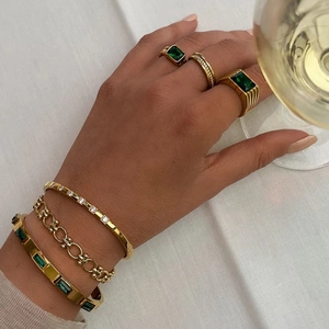 Gold stainless steel jewelry set featuring emerald green zircon accents on bracelets and rings